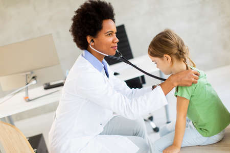 Cute little girl at the pediatrician examination by African american female doctorの写真素材