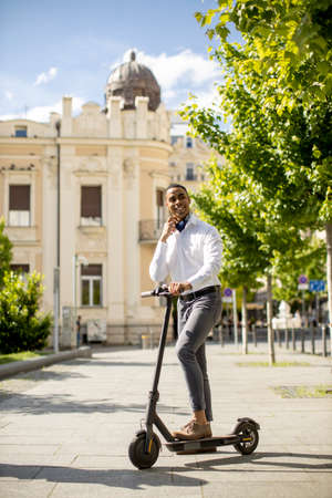 Handsome young African American using electric scooter on a streetの写真素材