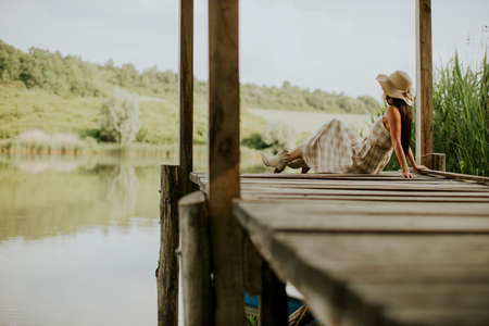 relaxing young woman on wooden pier at the calm lakeの写真素材