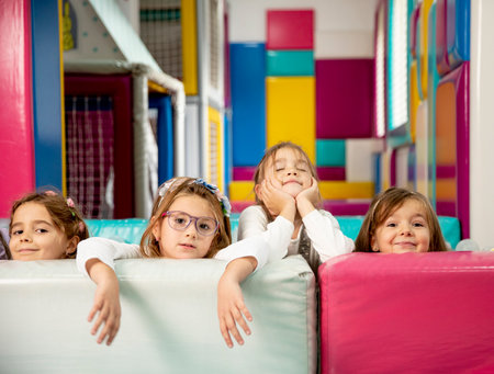 Group of cute little girls hiding behind large colorful leather blocksの写真素材