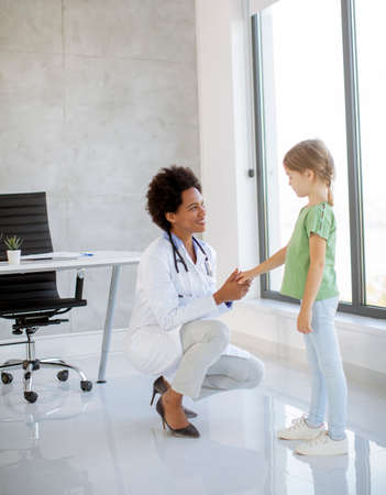 Cute little girl at the pediatrician examination by African american female doctorの写真素材