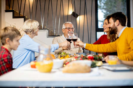 Happy family having a dinner with red wine at home