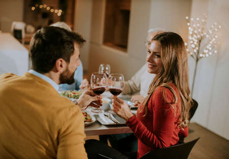 Happy family having a dinner with red wine at homeの写真素材
