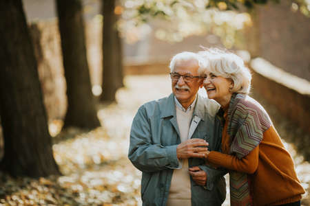 Handsome senior couple walking in autumn parkの写真素材
