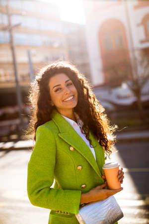 Pretty young woman holding takeaway coffee on the streetの写真素材