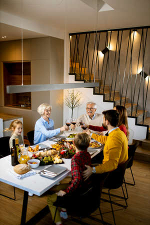 Happy family having a dinner with red wine at homeの写真素材