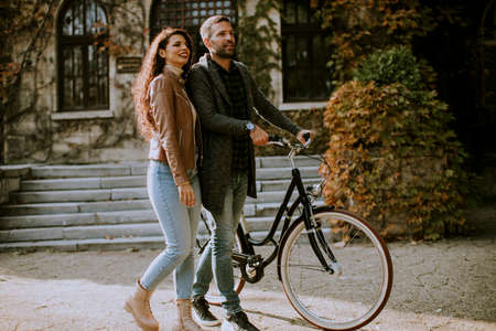Handsome young couple walking with bicycle in autumn parkの写真素材