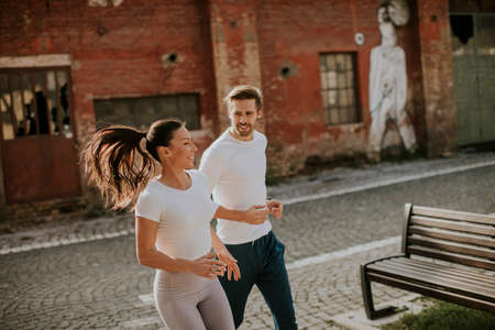 Handsome young fitness couple running in urban areaの写真素材