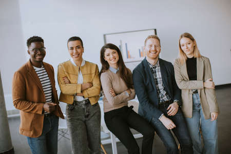 Group of positive businesspeople standing together in the office with their young female bussines leaderの写真素材