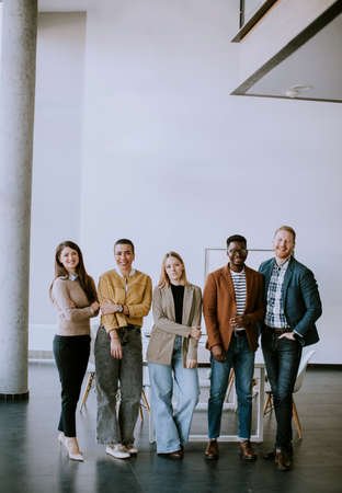 Group of young positive businesspeople standing together in the officeの写真素材