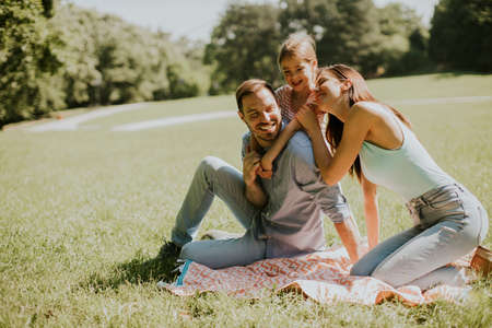 Happy young family with cute little daughter having fun in park on a sunny dayの写真素材