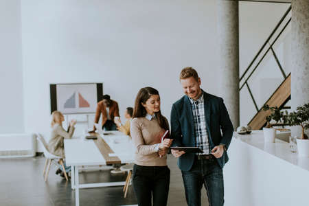 Young entrepreneurs walking together and using digital tablet in the modern officeの写真素材