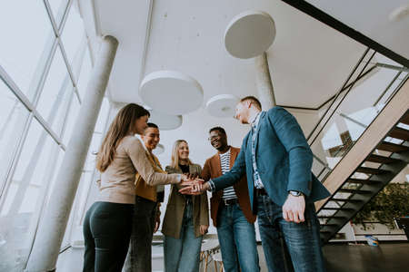Group of young positive businesspeople standing together in the officeの写真素材