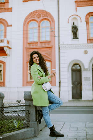 Pretty young woman on the street holding takeaway coffee