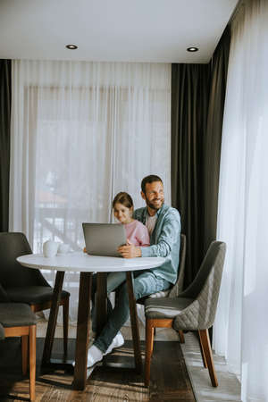 Father and daughter using laptop computer together in the roomの写真素材