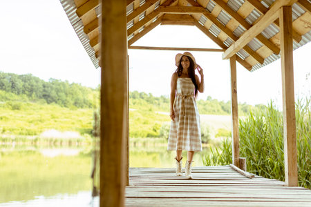 Young woman walking on the wooden pier at the calm lake on a hot summer dayの写真素材