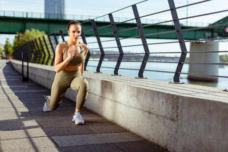 Pretty young woman in sportswear stretching on a river promenadeの写真素材