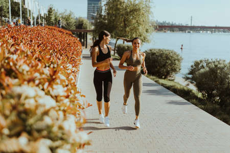 Pretty young woman taking running exercise by the river promenade