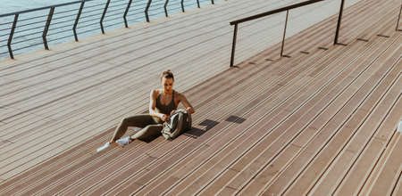 Pretty young woman takes a break after running in the urban area