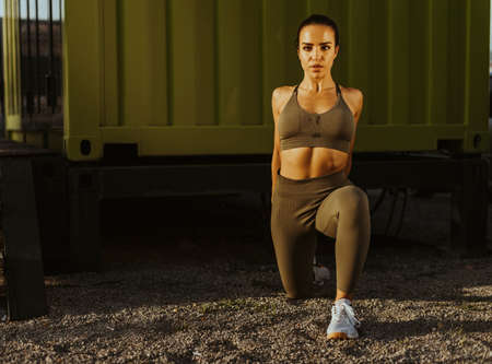 Pretty young woman in sportswear exercising at urban environment