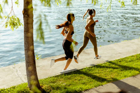 Pretty young woman taking running exercise by the river promenade
