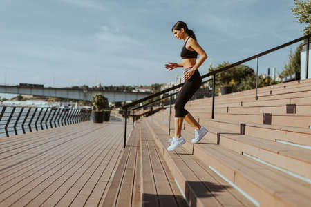 Pretty young woman in sportswear exercising on a river promenadeの写真素材