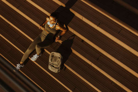 Over view at pretty young woman takes a break after running in the urban area