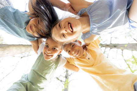 Group of cute asian and caucasian happy kids huddling, looking down at camera and smilingの写真素材