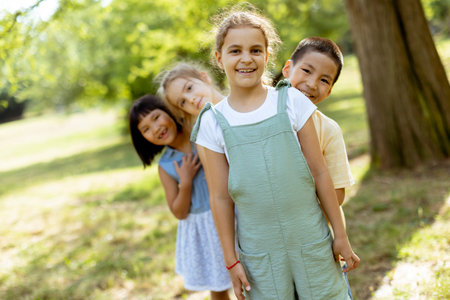 Group of cute asian and caucasian happy kids huddling, looking down at camera and smilingの写真素材