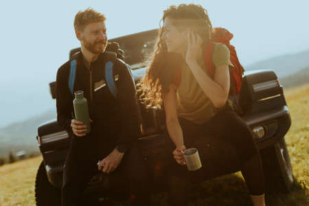 Handsome young couple relaxing on a terrain vehicle hood at countrysideの写真素材