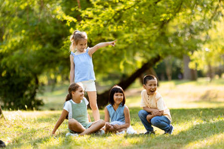 Group of cute asian and caucasian kids having fun in the parkの写真素材