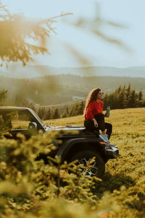 Pretty young woman relaxing on a terrain vehicle hood at countrysideの写真素材