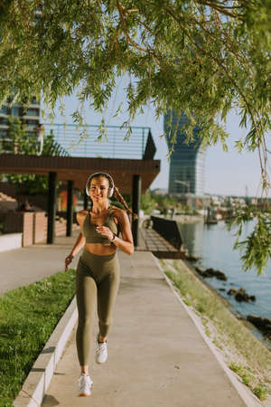 View at active young beautiful woman running on the promenade along the riversideの写真素材