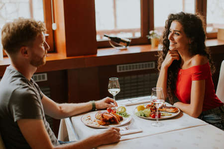 young couple having lunch with white wine in the restaurantの写真素材
