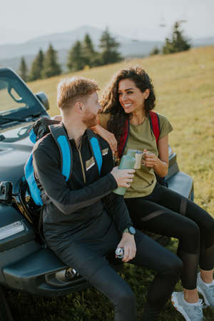 Handsome young couple relaxing on a terrain vehicle hood at countryside
