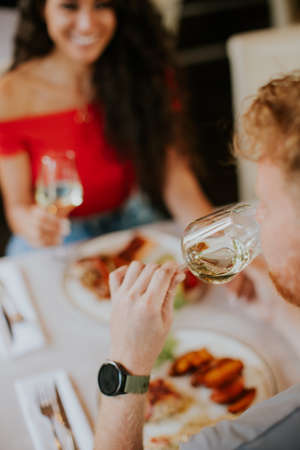 Handsome young couple having lunch with white wine in the restaurantの写真素材