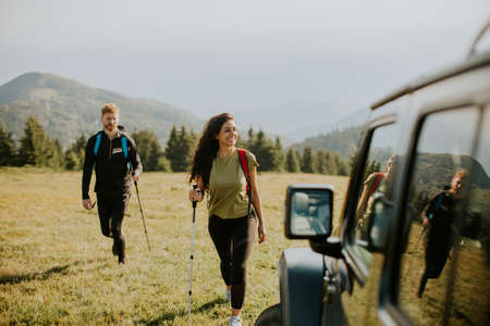 Smiling young couple walking with backpacks over green hills