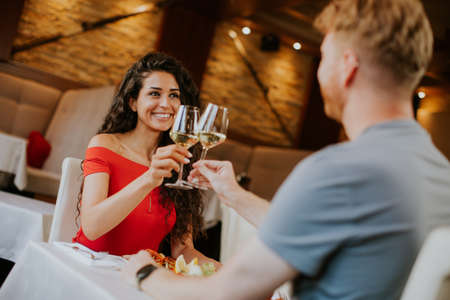 young couple having lunch with white wine in the restaurantの写真素材