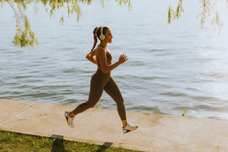 View at active young beautiful woman running on the promenade along the riversideの写真素材