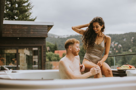Attractive young couple enjoying in outdoor hot tub on vacationの写真素材
