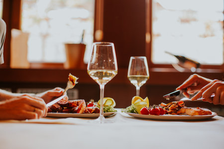 Handsome young couple having lunch with white wine in the restaurantの写真素材