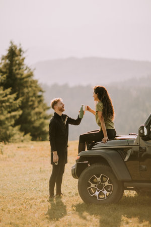 Handsome young couple relaxing on a terrain vehicle hood at countrysideの写真素材
