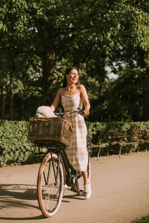 Pretty young woman with white bichon frise dog in the basket of electric bikeの写真素材