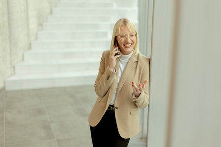Businesswoman using mobile phone while standing on the modern office hallway