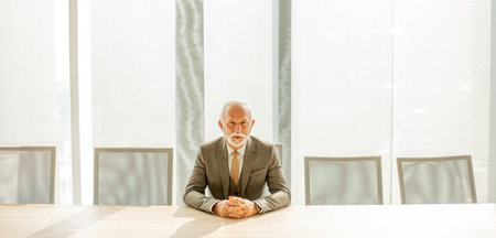 Handsome senior business man sitting in the boardroom at the officeの写真素材