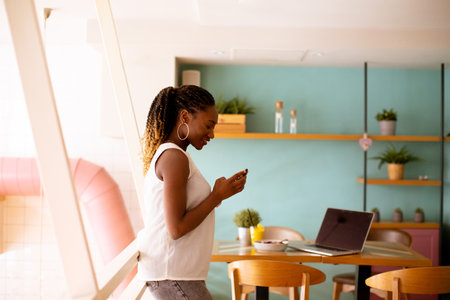 Pretty young black woman using mobile phone in the cafeの写真素材