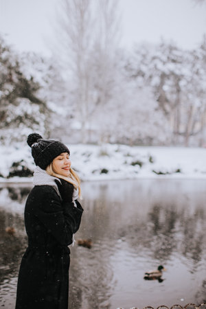 Pretty young woman in warm clothes enjoying in snowの写真素材