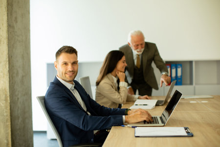 Handsome young business man using laptop computer in the officeの写真素材