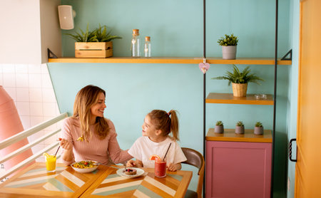 Mother and daughter having good time during breakfast with fresh squeezed juices in the cafeの写真素材