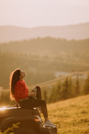 Pretty young woman relaxing on a terrain vehicle hood at countrysideの写真素材
